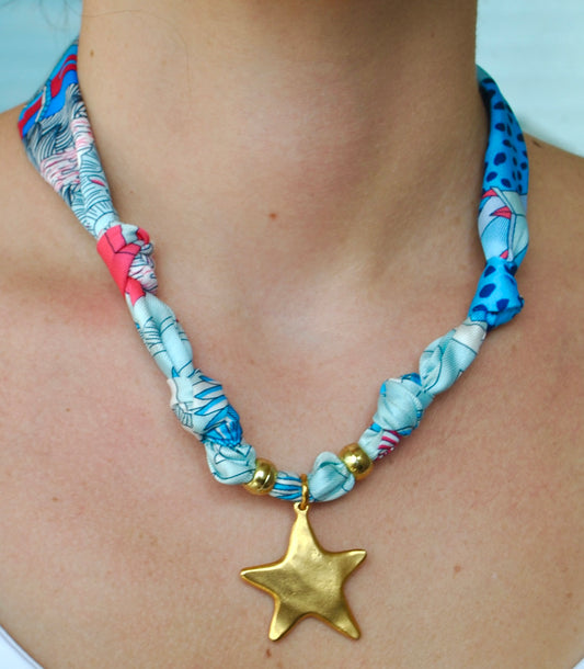 Blue floral and coral silk scarf necklace with matte gold star pendant worn around neck