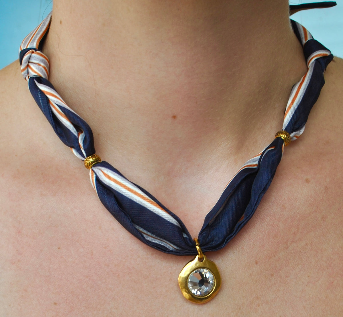 Navy white and orange stripe silk scarf necklace with gold bezel crystal pendant worn around neck