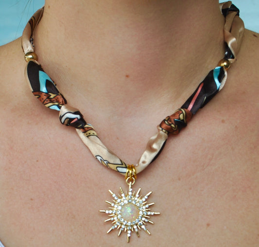 Taupe multicolor printed silk scarf necklace with large crystal sunburst and opal pendant worn around neck